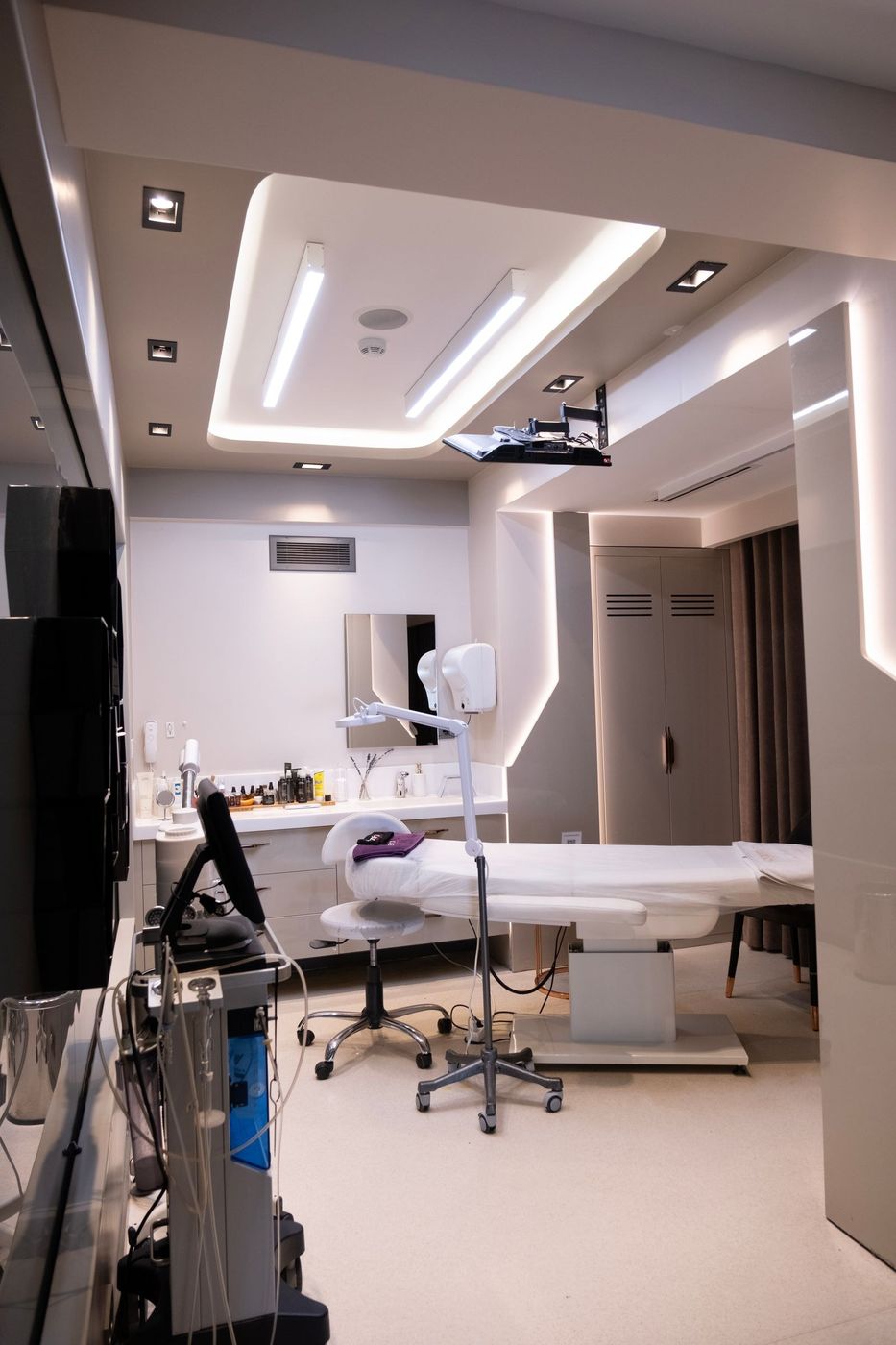 Sala de atendimento vazia, com maca e luminária de estúdio