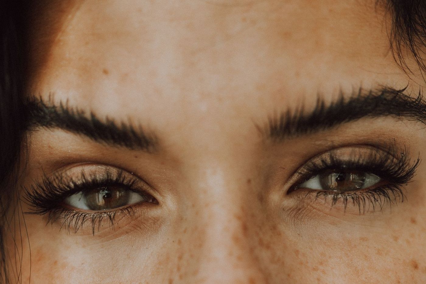Close dos olhos de uma mulher com sardas e os cílios feitos